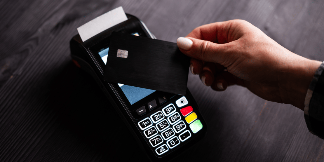 Hand holding a credit card above a POS terminal for secure EMV chip payment, representing POS Level 3 certification requirements.